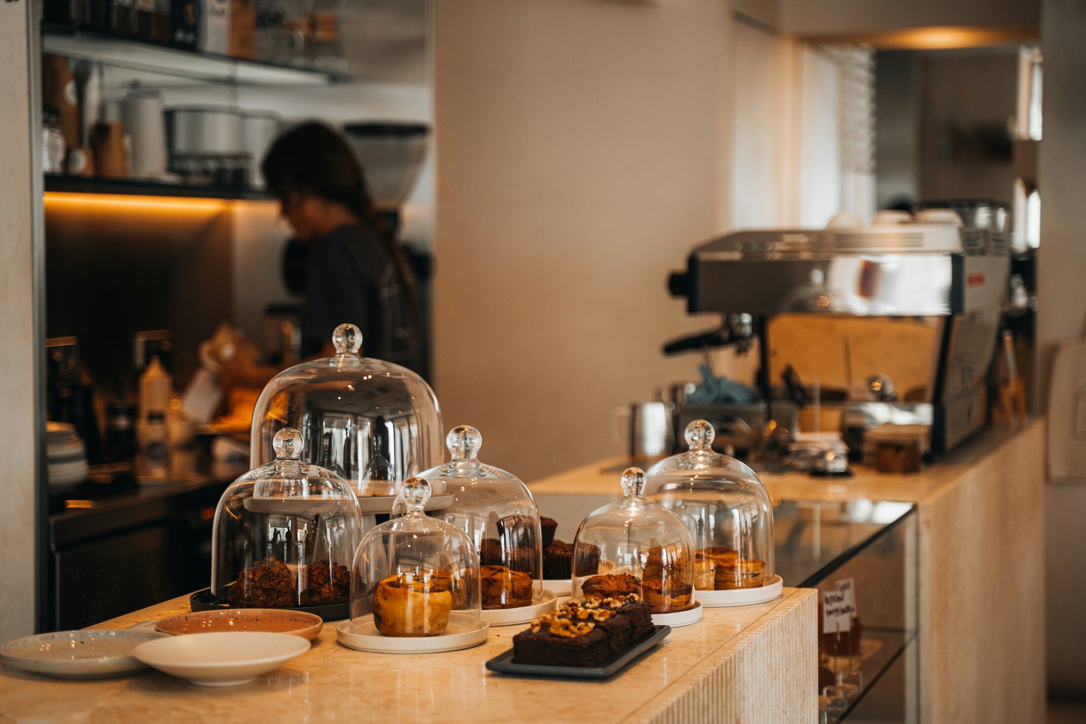 Pastries displayed under glass domes on a cafe counter.
