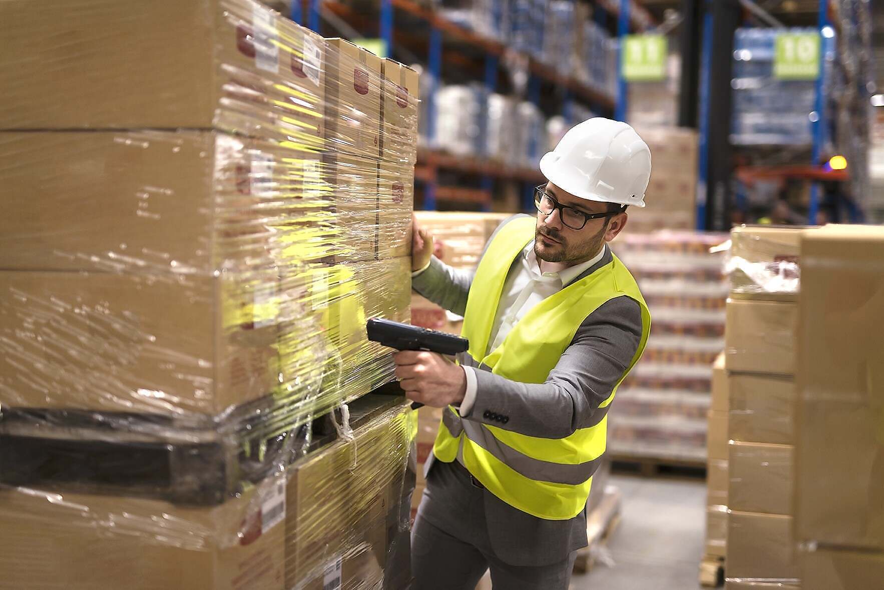 Male warehouse worker using bar code scanner to analyze newly ar