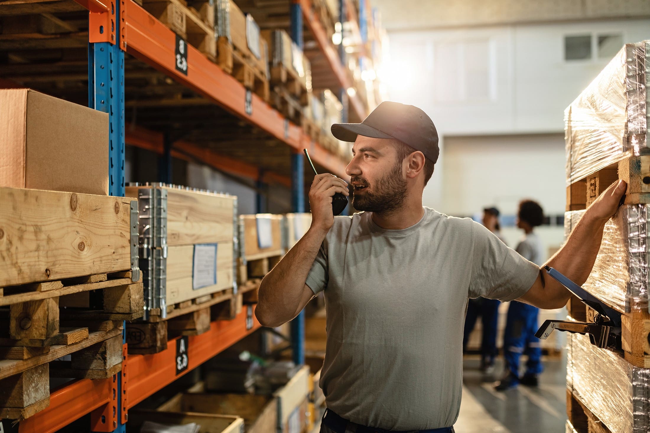 Young worker using walkie-talkie while working in a warehouse.